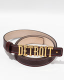 The Alta Moda Belt by FashionInternational is a brown leather accessory featuring a gold buckle that spells "DETROIT," highlighting exquisite Italian craftsmanship.