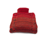 Turtle Neck by Fashion International, a red knitted hot water bottle cover featuring a cable pattern and a rolled neck, displayed flat on a white background.